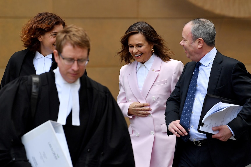 Lisa Wilkinson arrives at court, flanked by lawyers.