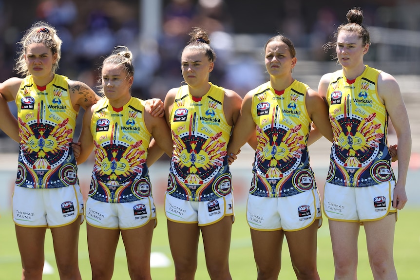 Crows players link arms while wearing their Indigenous guernseys