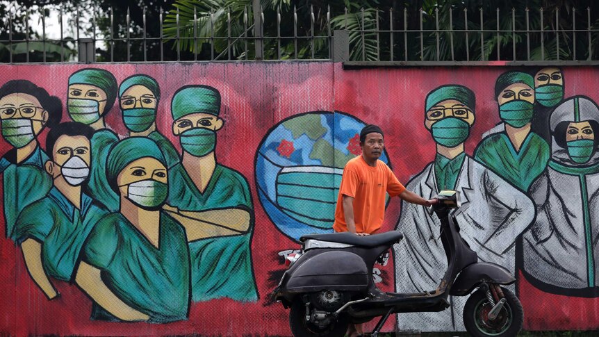 A motorists stops near a mural painted as a tribute to medical workers in Indonesia.