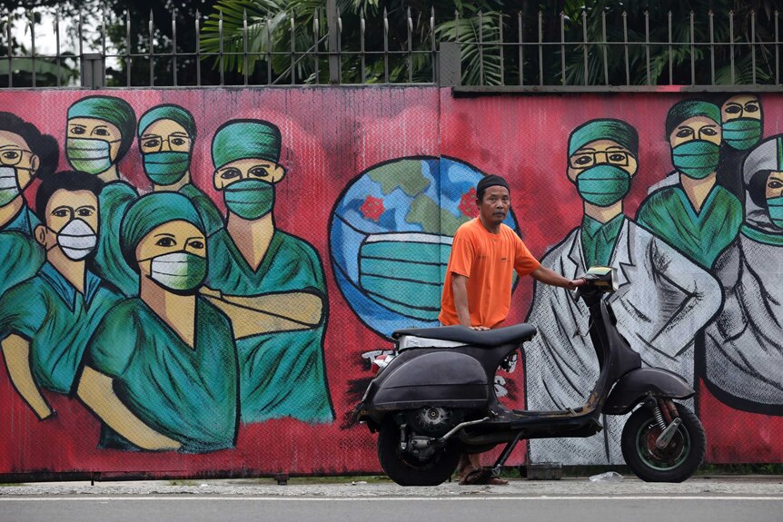 A motorists stops near a mural painted as a tribute to medical workers in Indonesia.