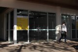 A photo of a vacant shopfront in Darwin's CBD as a man in businesswear walks past.
