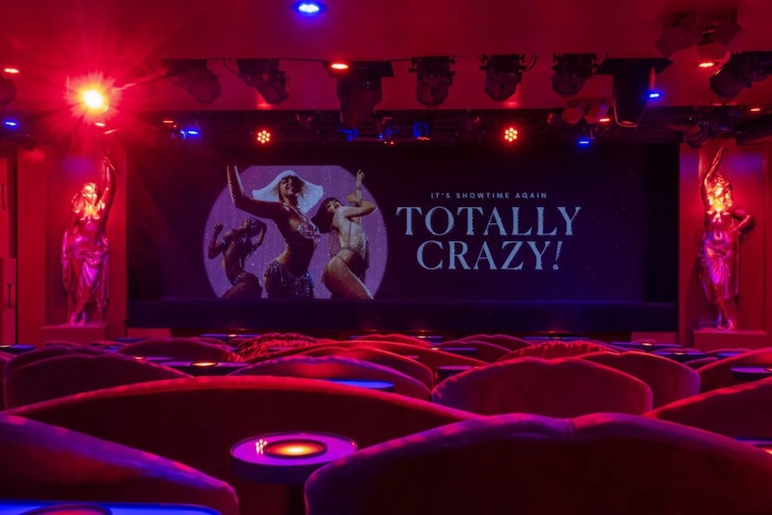 Seats under red lighting with a screen showing dancers and the words "Totally Crazy!"