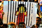 Moamar Gaddafi cartoon is held up in the crowd gathered in Benghazi