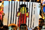 Moamar Gaddafi cartoon is held up in the crowd gathered in Benghazi