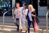 Lady in sunglasses walking out with two other women