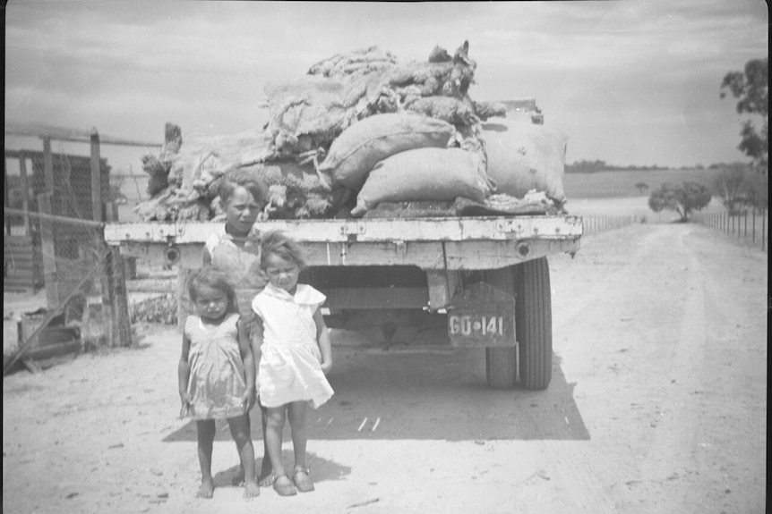 Aboriginal children stand near a truck at a reserve.