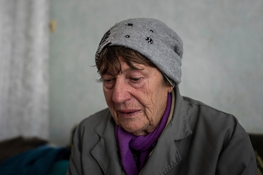 An elderly Ukrainian woman cries as she looks down.