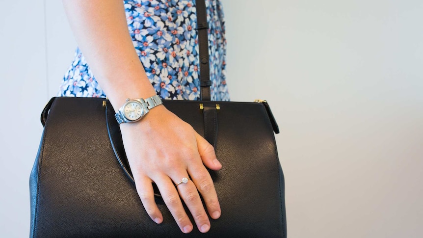 A woman holding a handbag with a diamond ring and watch.