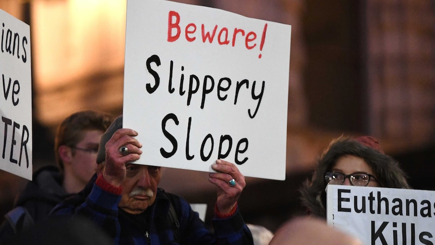 A pro-life demonstrator at a rally holds up a white sign reading "Beware! Slippery slope".