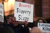 A pro-life demonstrator at a rally holds up a white sign reading "Beware! Slippery slope".