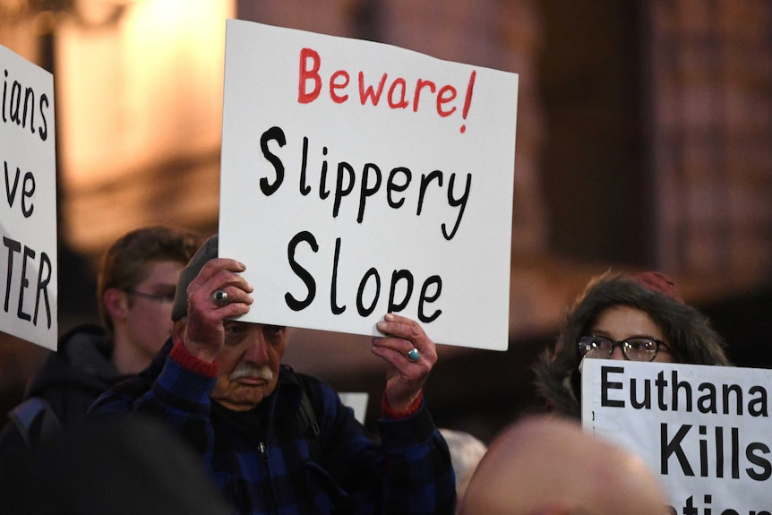 A pro-life demonstrator at a rally holds up a white sign reading "Beware! Slippery slope".