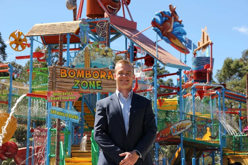 A man stands in front of a ride at a water park.