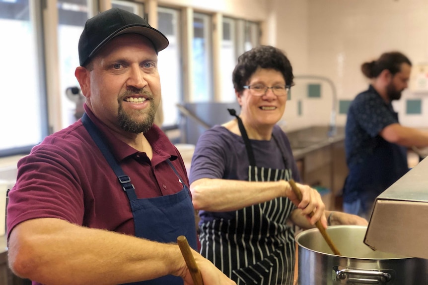 Volunteers stand in a kitchen cooking food for a charity program in Broome, Western Australia.