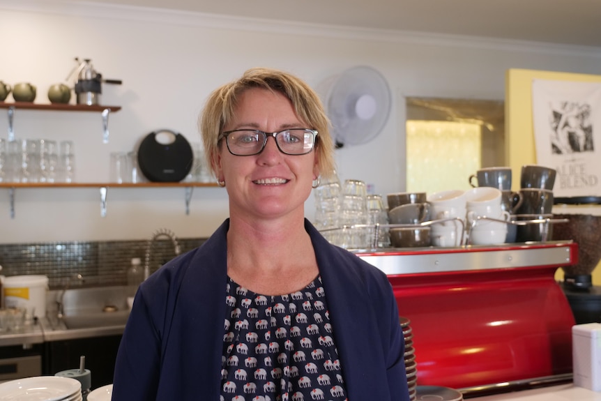 Kim Hopper stands in front of a red coffee machine.