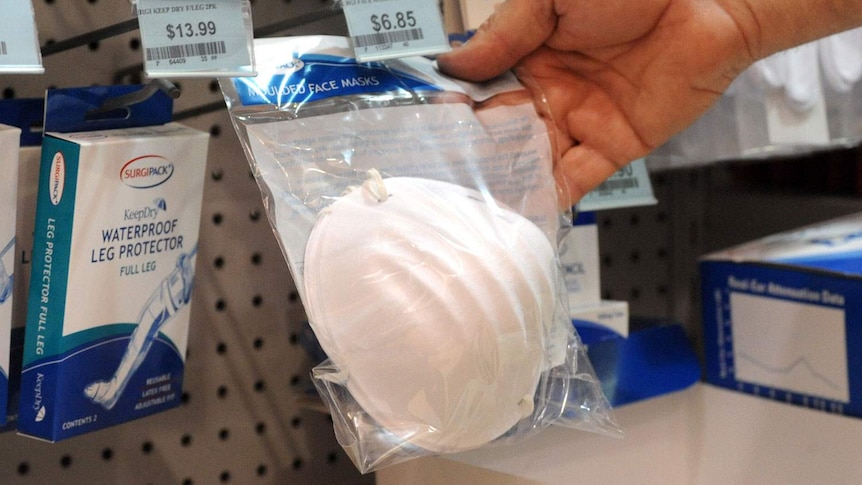 A customer takes a facemask off the shelf at a shop.