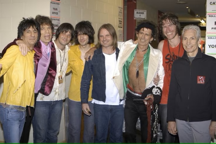 Rolling Stones band members pose with You Am I band members, arms around each other.