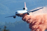 A very large air tanker drops red fire retardant on a forest fire.