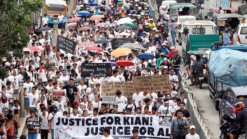 A crowd of mourners pack the streets and wave signs during a funeral march for Kian delos Santos.