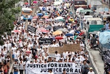 A crowd of mourners pack the streets and wave signs during a funeral march for Kian delos Santos.