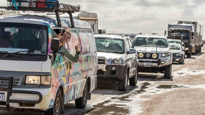 A passenger in a van gives the thumbs up amidst a traffic jam.