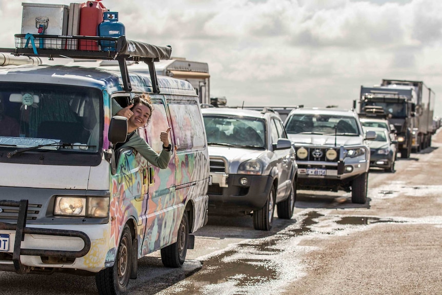 A passenger in a van gives the thumbs up amidst a traffic jam.