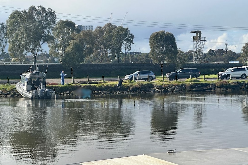 police investigator, cars and a boat on the shore of maribyrnong river in flemington, melbourne