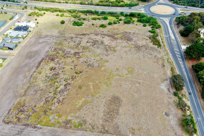An aerial shot of a vast and empty plot of land covered in grass.