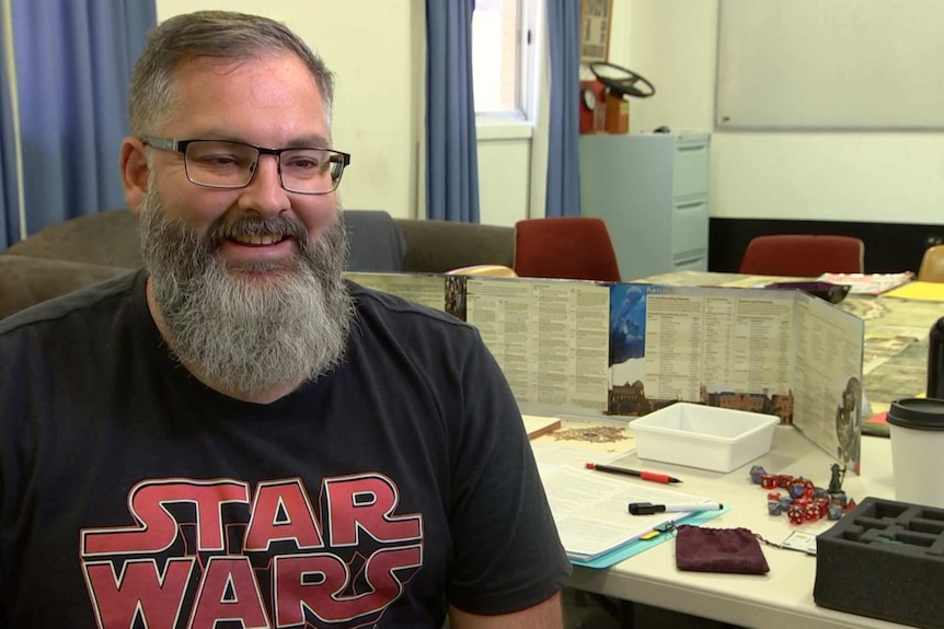 Ian smiles while sitting near the game board.