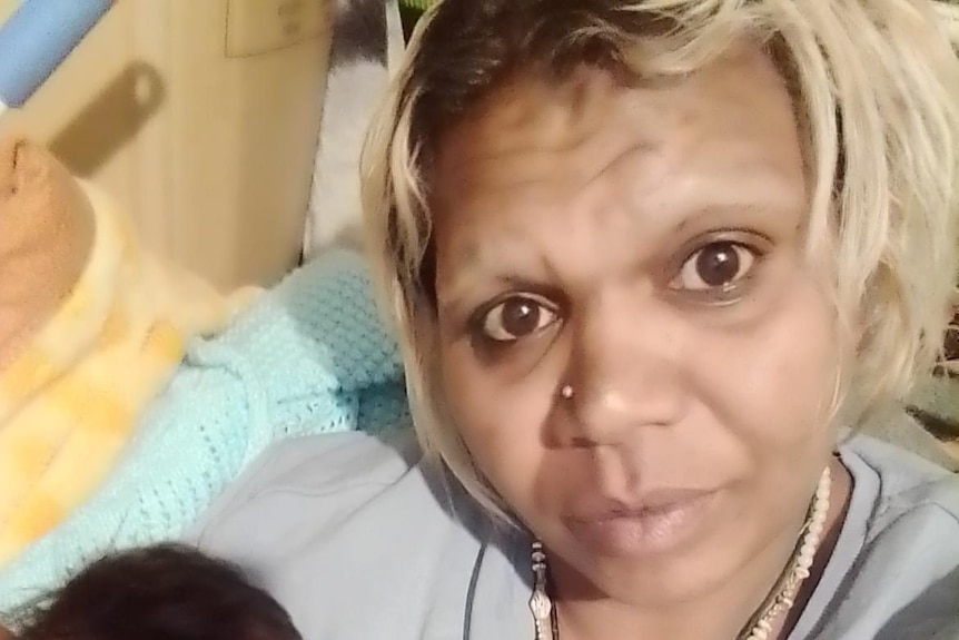 A tight head shot of an Aboriginal woman with dyed blonde hair.