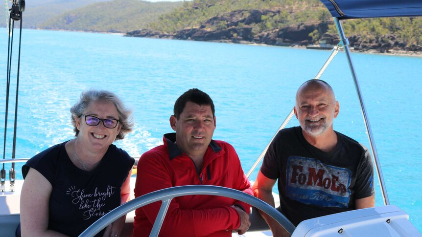 Justine Barwick, Craig Barwick and John Hadok sit in a boat, smiling at the camera.