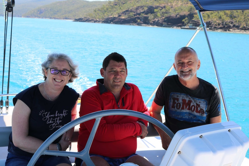 Justine Barwick, Craig Barwick and John Hadok sit in a boat, smiling at the camera.