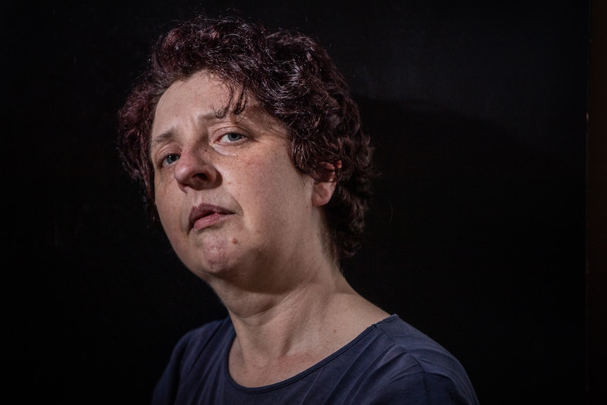 A headshot of a woman with a black background