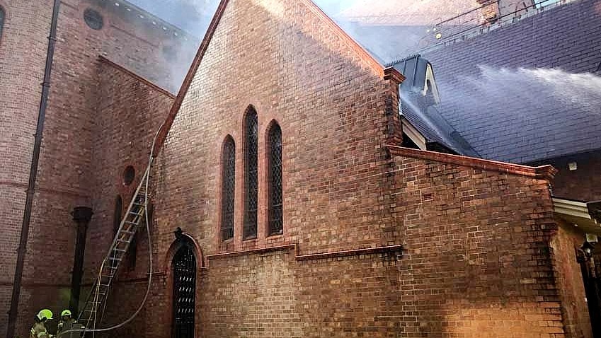 Firefighters hose down a church hit by an arson attack