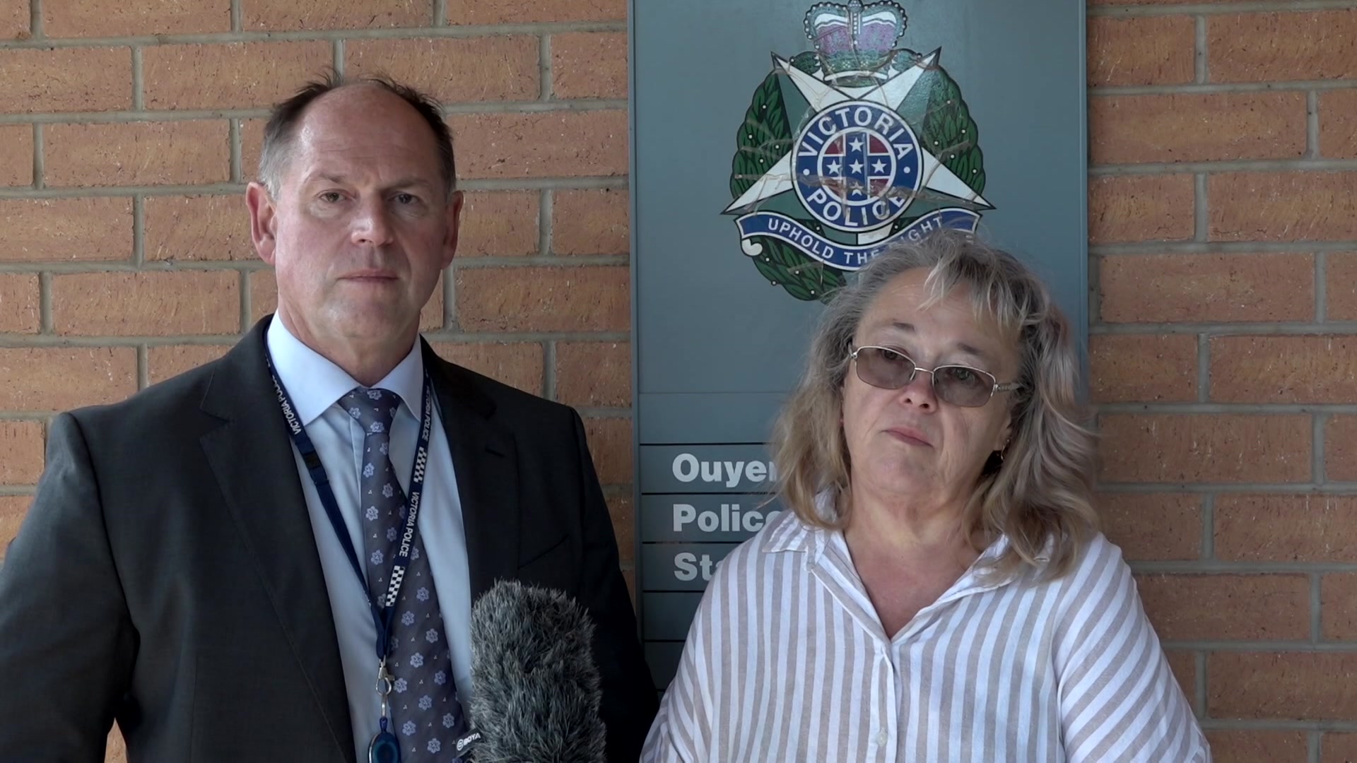 Woman wearing glasses standing next to police officer