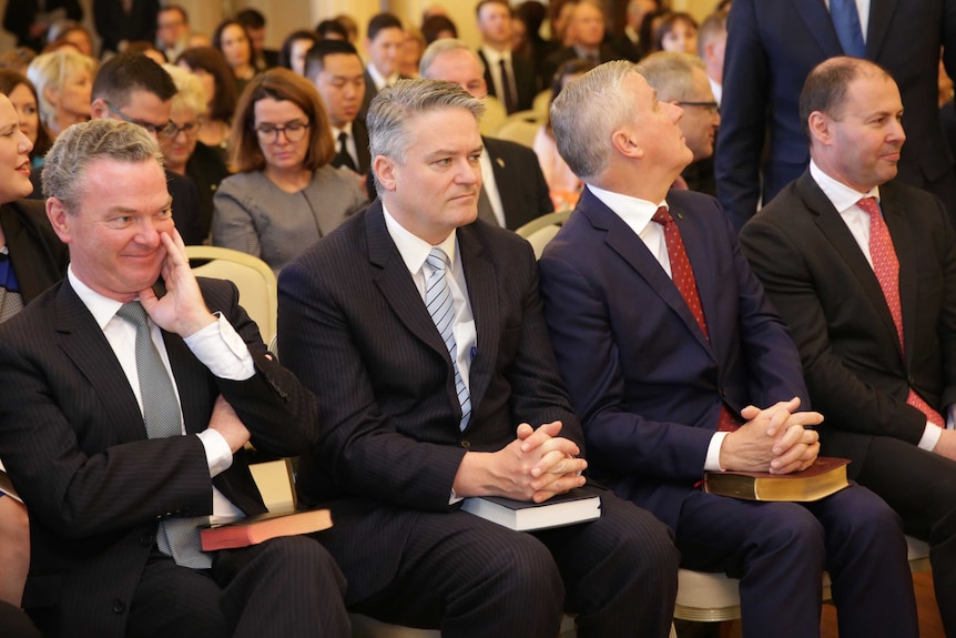 Mathias Cormann sits in a room alongside other ministers