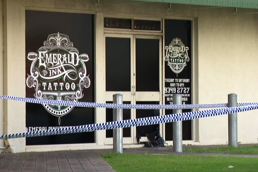 The front of a tattoo shop with police tape in front of it.