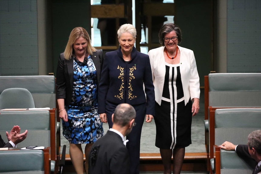 Three women smile as they walk into the House of Representatives