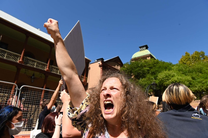 A woman shouts and holds her fist in the sky.