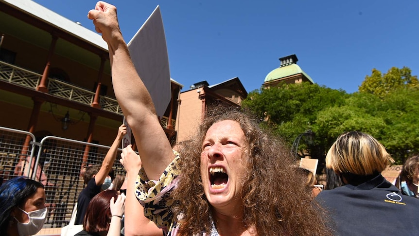 A woman shouts and holds her fist in the sky.