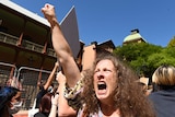 A woman shouts and holds her fist in the sky.