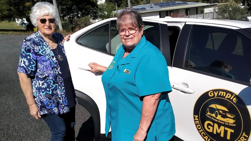 two women stand at car with door open