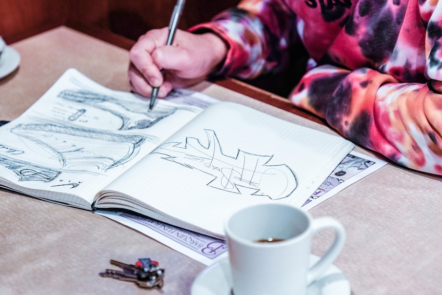 A man sketching a shoe on notebook.