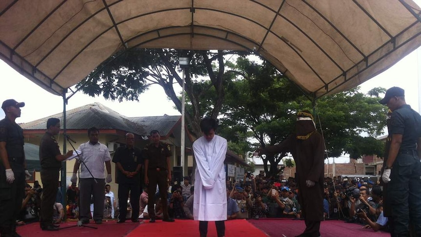 A man stands as he is flogged in Aceh, Indonesia.