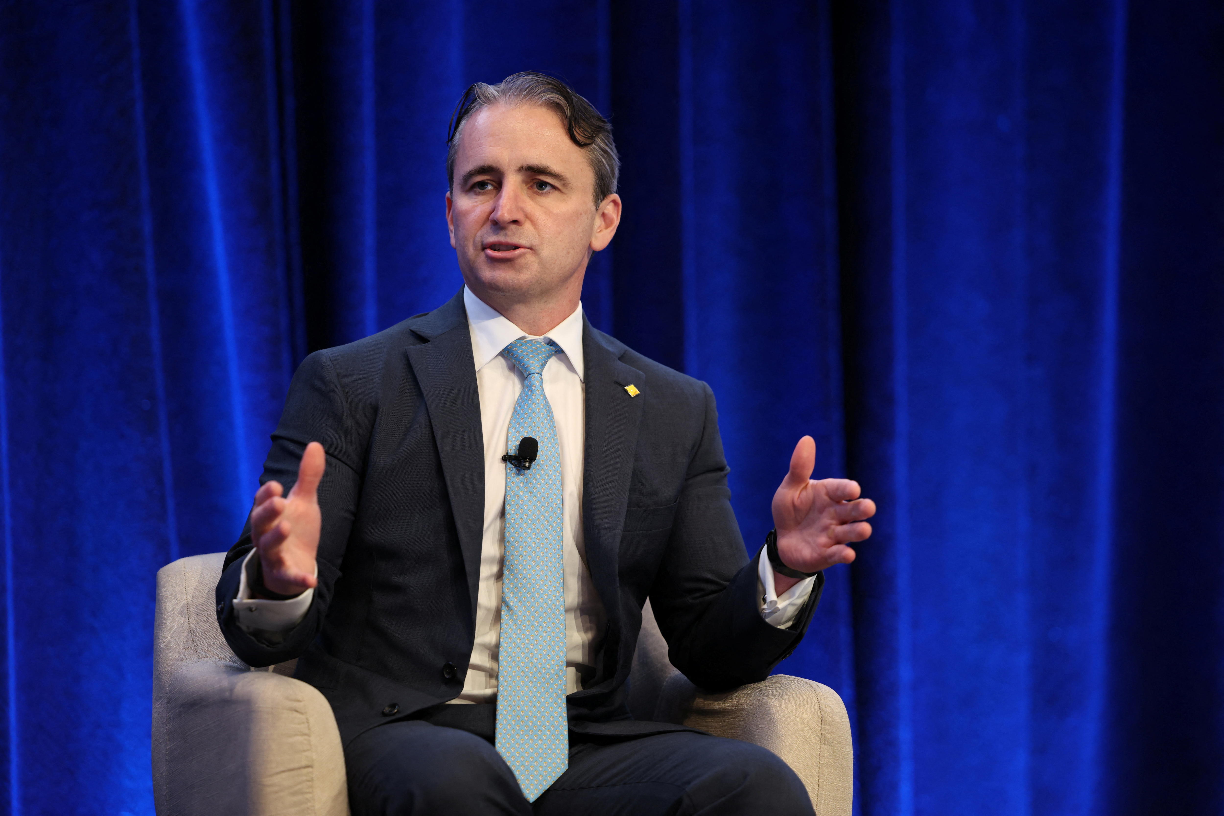 Matt Comyn, wearing a suit and tie, gestures with his hands.