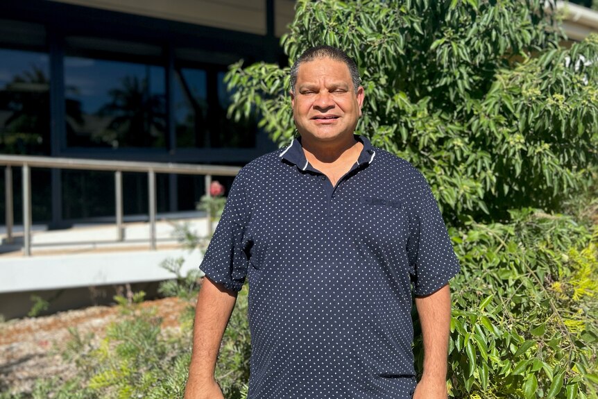 An Aboriginal man standing in front of a bush
