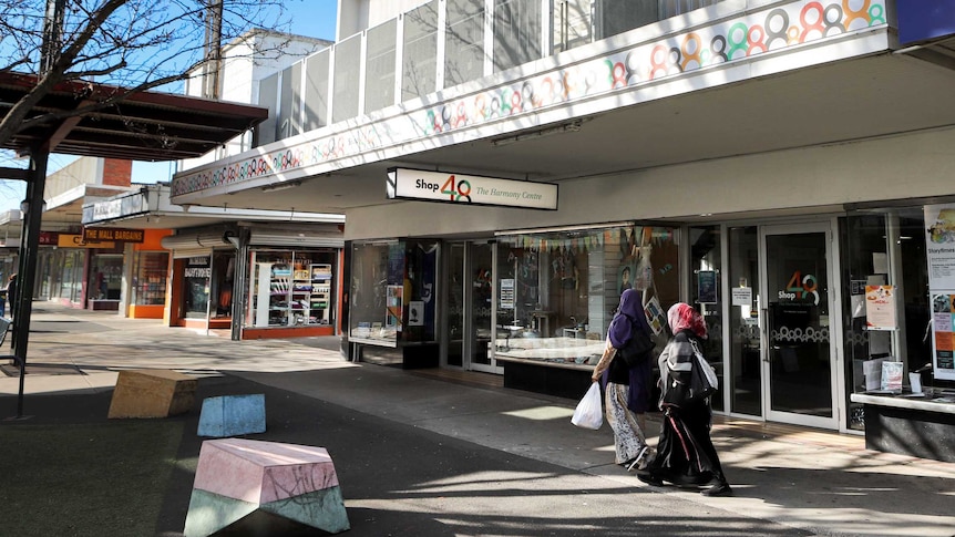 A shopping strip with two women walking past.