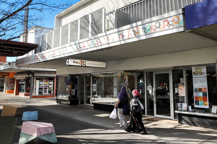 A shopping strip with two women walking past.