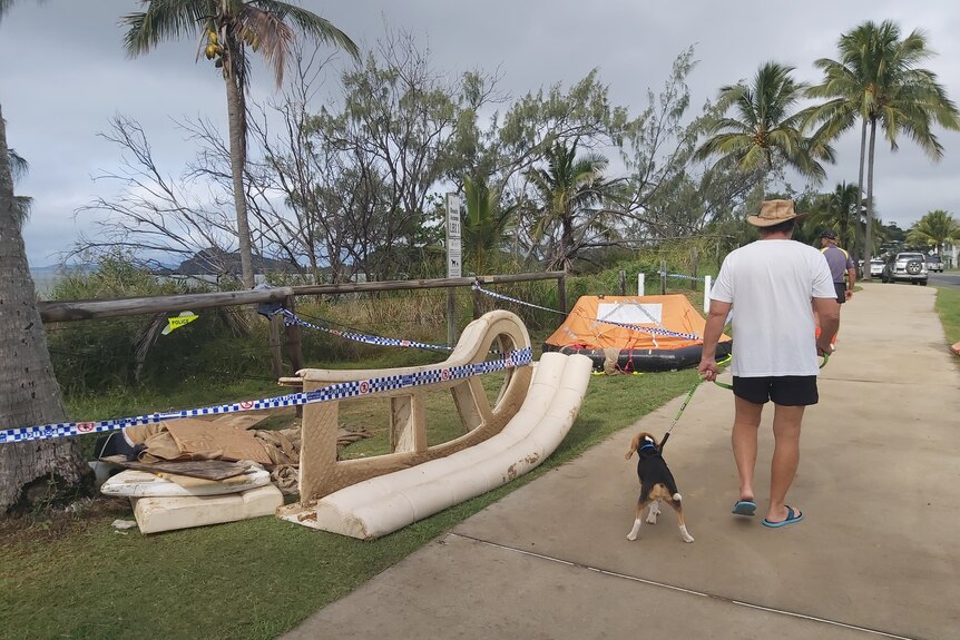 Boat debris behind police tape on a footpath next to a beach