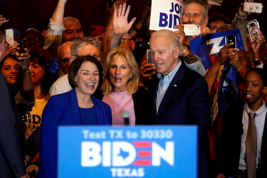 Joe Biden with his wife Jill and Amy Klobuchar surrounded by supporters