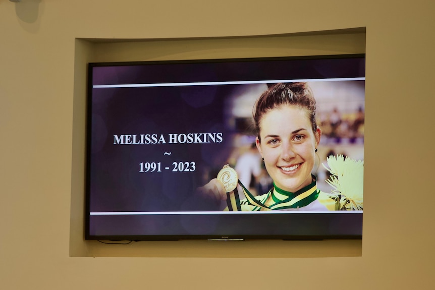 An image on a screen of a woman clutching a medal and the words 'Melissa Hoskins - 1991-2023'